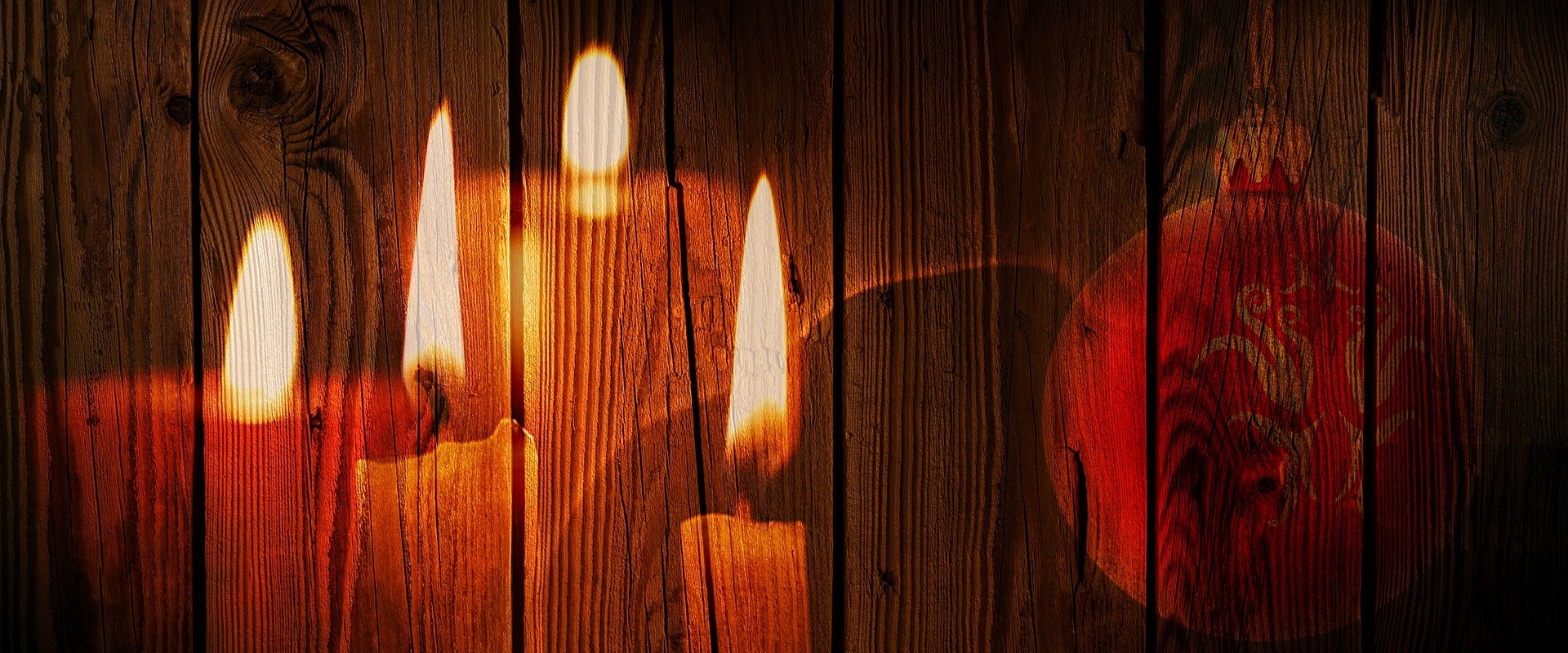 Kerzen und eine Weihnachtskugel spiegeln sich an einer Wand. 