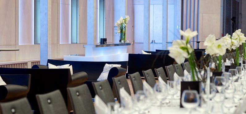 Raiffeisen-Saal Catering Gala eckige Tische eingedeckt und Loungemobiliar schwarz-weiß Forum Altötting
