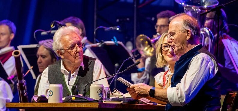 Opern auf Bayrisch, Gerd Anthoff, Monika Gruber, Michael Lerchenberg, Kultur+Kongress Forum Altötting, Foto SFS Regensburg Conny Glogger, Gerd Anthoff, Michael Lerchenberg sitzen zusammen an einem Tisch.