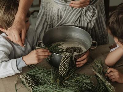Sinnesreise durch den Wald Stadtgalerie Altötting, Foto ? Eine Frau und zwei Kinder stehen vor einem Topf mit Nadeln und Tannenzapfen.