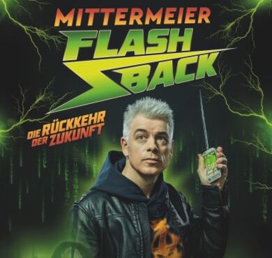 Michael Mittermeier, Flashback, Forum Altötting, Foto Mittermeier Der Comedian Michael Mittermeier steht vor einem dunklen Hintergrund und hält eine altmodische Fernbedienung in der Hand.
