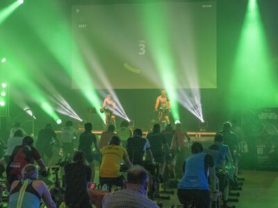 Raiffeisen-BRK Charity-Ride, Forum, Altoetting, Foto Veranstalter Menschen auf Fahrrädern in einer Halle