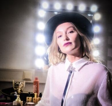 Malarina, KULTUR+KONGRESS FORUM ALTÖTTING, Foto: Christopher Glanzl Die junge Kabarettistin Malarina posiert mit Hut vor einem Garderobenspiegel.