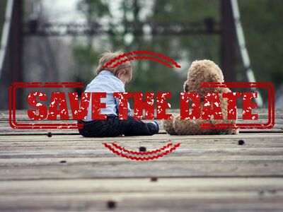 Ein kleiner Junge sitzt mit einem Teddybär auf einem Holzboden