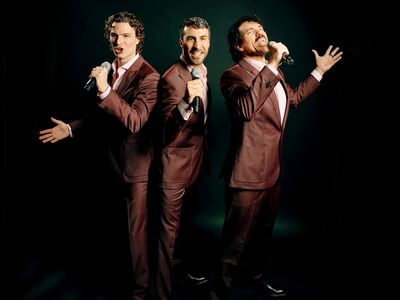 Impulso Tenors, Forum Altoetting, Bild Europolis Drei Männer in braunen Anzügen singen in ihre Mikrofone.