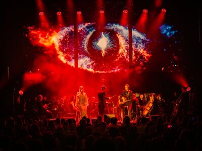 Ein Orchester steht vor einer Lichtprojektion.