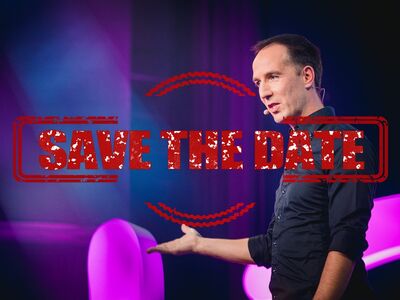 Ein Mann in dunklem Hemd vor einem bunten Hintergrund.