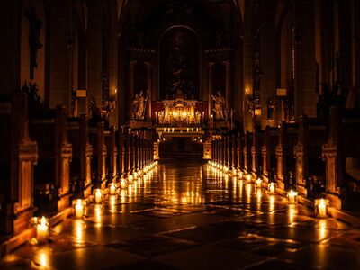 Vom Tod zum Leben, Transitus, Fest der Sinne, Altoetting, Bild Tom Bauer Ein Mittelgang in der einer Kirche nur mit Kerzen beleuchtet.