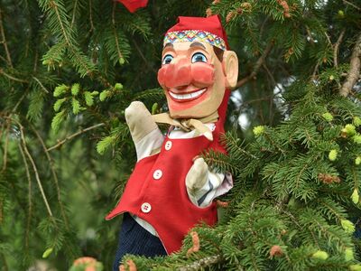 Eine Handpuppe vor einem Weihnachtsbaum.