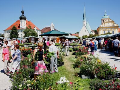 Blumen, Menschen und Gebäude auf dem Altöttinger Kapellplatz.