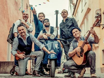 6 Männer auf einer Straße mit einer Vespa.