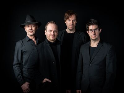 Vier Männer in schwarzen Anzügen.