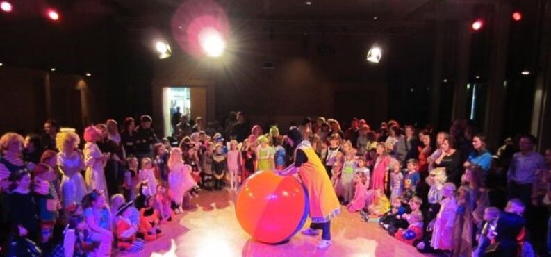 Eine Gruppe von Kindern stehen verkleidet um einen Clown.