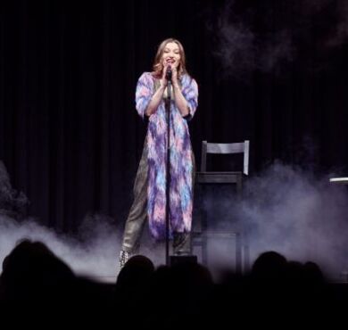 Malarina, KULTUR+KONGRESS FORUM ALTÖTTING, Foto: Ernesto Gelles Die junge Kabarettistin Malarina steht auf der Bühne am Mikro im Nebel.