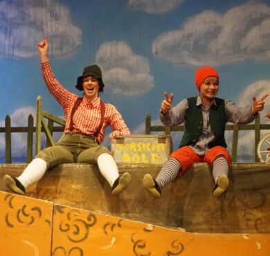 Kasperl und Seppel sitzen auf der Wiese.