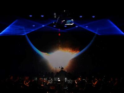 The Music of Hans Zimmer, KULTUR+KONGRESS FORUM ALTÖTTING, Foto Star Entertainment Ein Orchester steht vor einer Lichtprojektion.