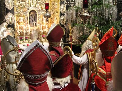 Nikoläuse in rotem Gewand in einer Kirche.
