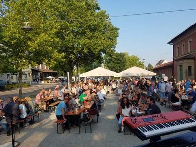 Viele Menschen sitzen im Sommer auf einem Platz. 