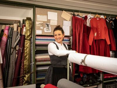 geführte Radltour Altötting zu Barbarino Trachten, Foto Julia Barbarino Eine Frau in Dirndl steht in einer Dirndlschneiderei.