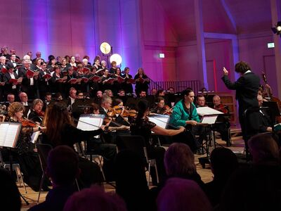 Euregio Oratorienchor, André Gold, Bad Reichenhaller Philharmoniker, Bild Irmi Mayer Chor, Orchester und Dirigent vor einer bunten Wand