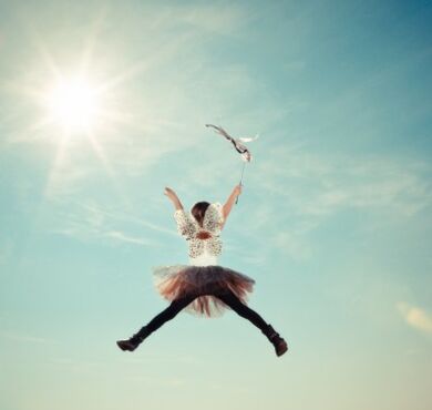 Kleines Mädchen springt im Faschingskostüm in die Luft.