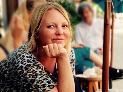 Eine Frau sitzt in einem Straßencafe.