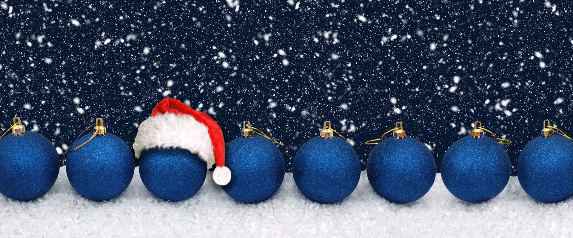 Blaue Weihnachtskugeln mit Schneeflocken im Hintergrund.