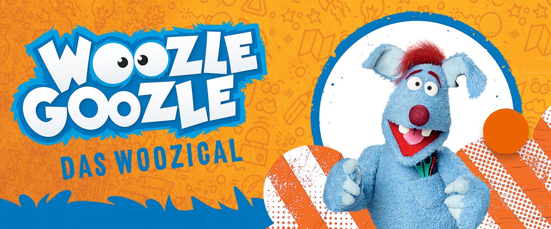 Das blaue Stofftier Woozzle Goozle lacht in die Kamera.