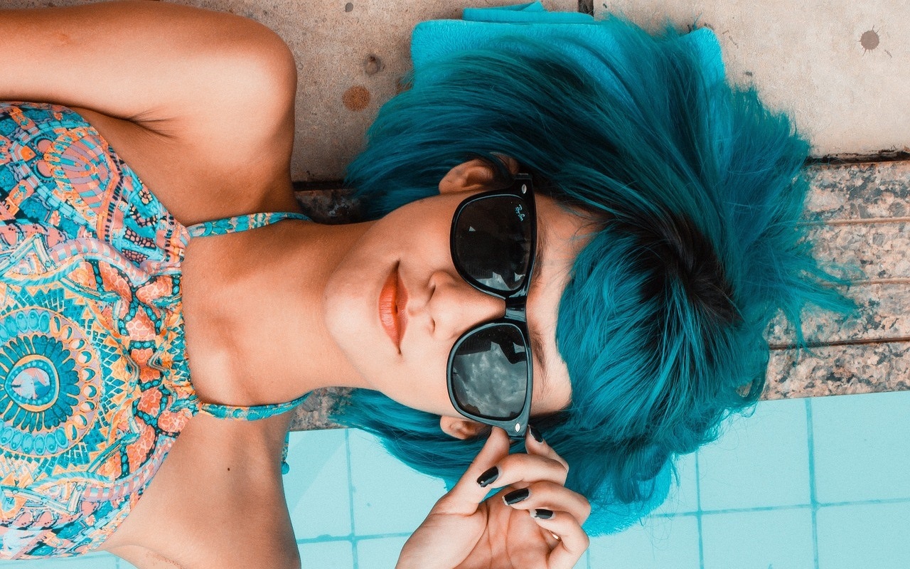 Eine junge Frau lingt am Swimming Pool und trägt auffällige Retro-Bademode .