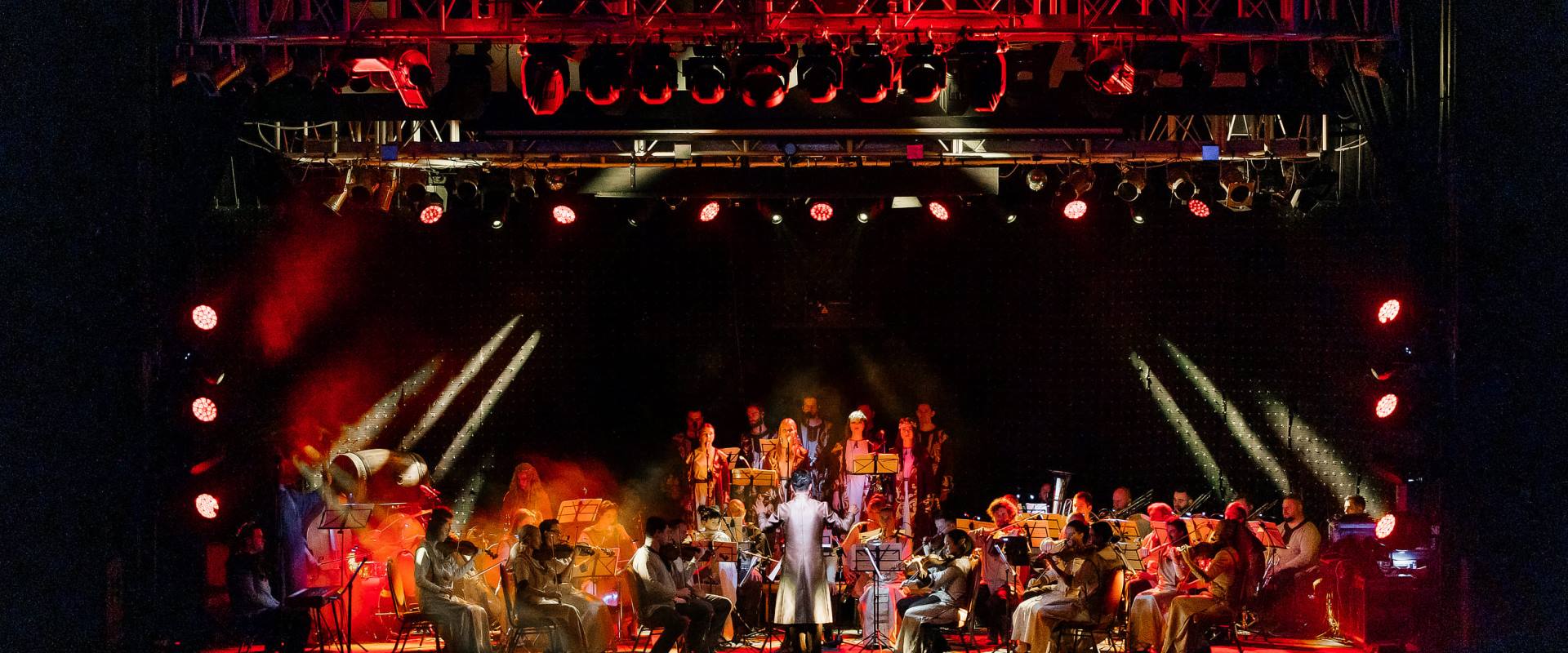 Ein großes Symphonieorchester auf der Bühne mit rotem Licht.