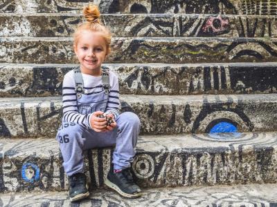 Kinderkleiderbasar, Kindergarten Regenbogen, Forum, Altötting, Bild Pixabay Ein kleines Mädchen sitzt vor einem Hintergrund mit viel Graffiti.