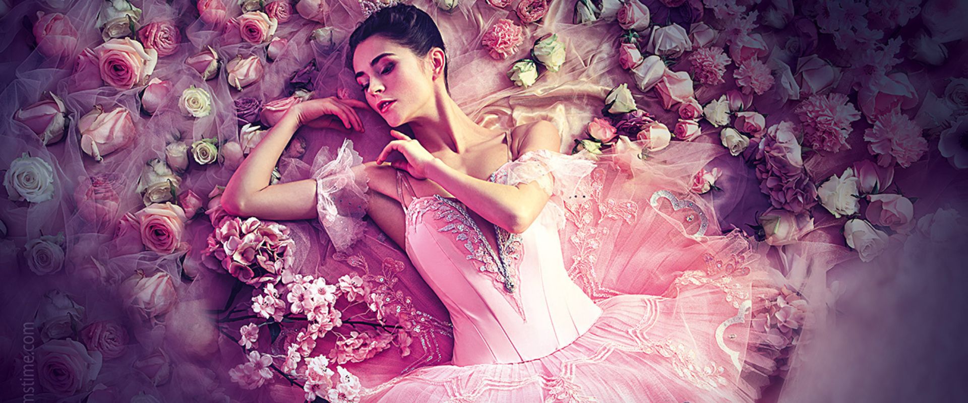 Eine Balletttänzerin liegt im Dornröschenkleid in einem Meer aus Blumen.