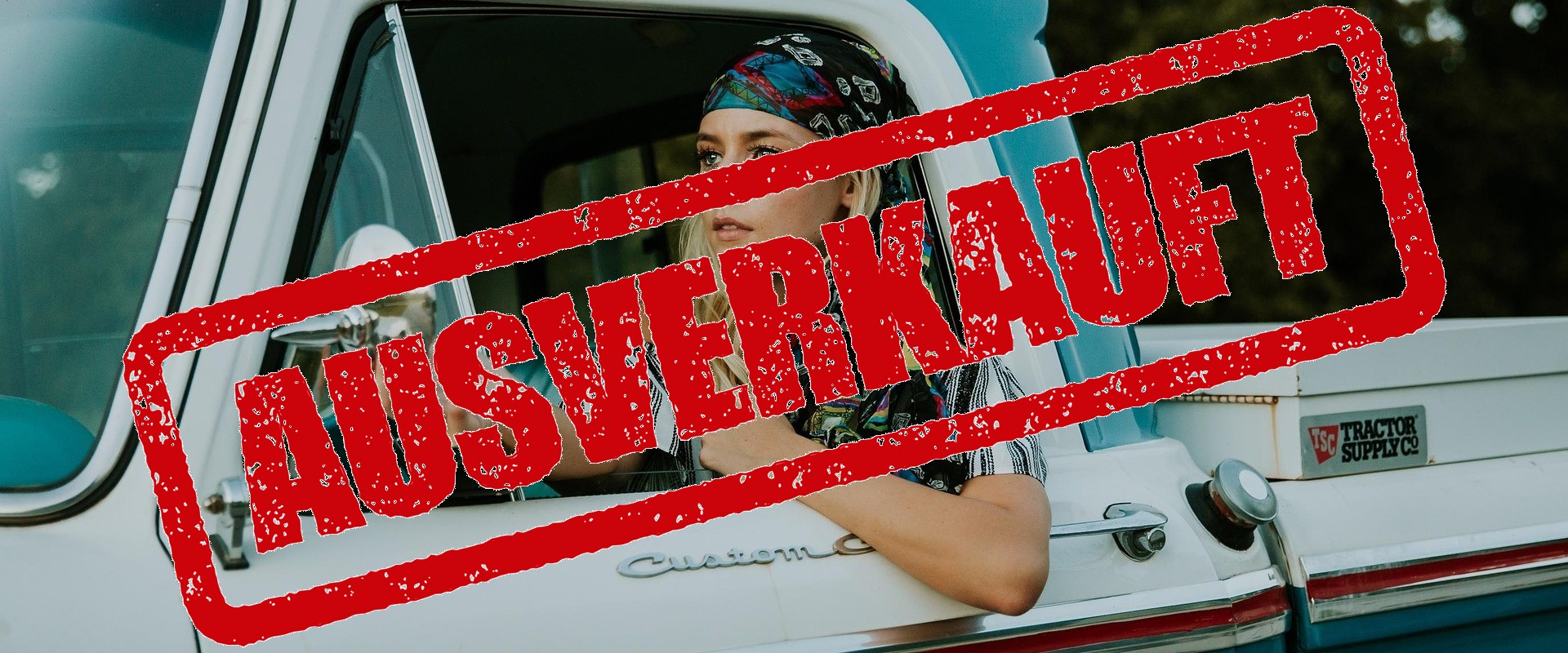 Eine junge Frau mit Kopftuch sitzt in einem alten Auto.