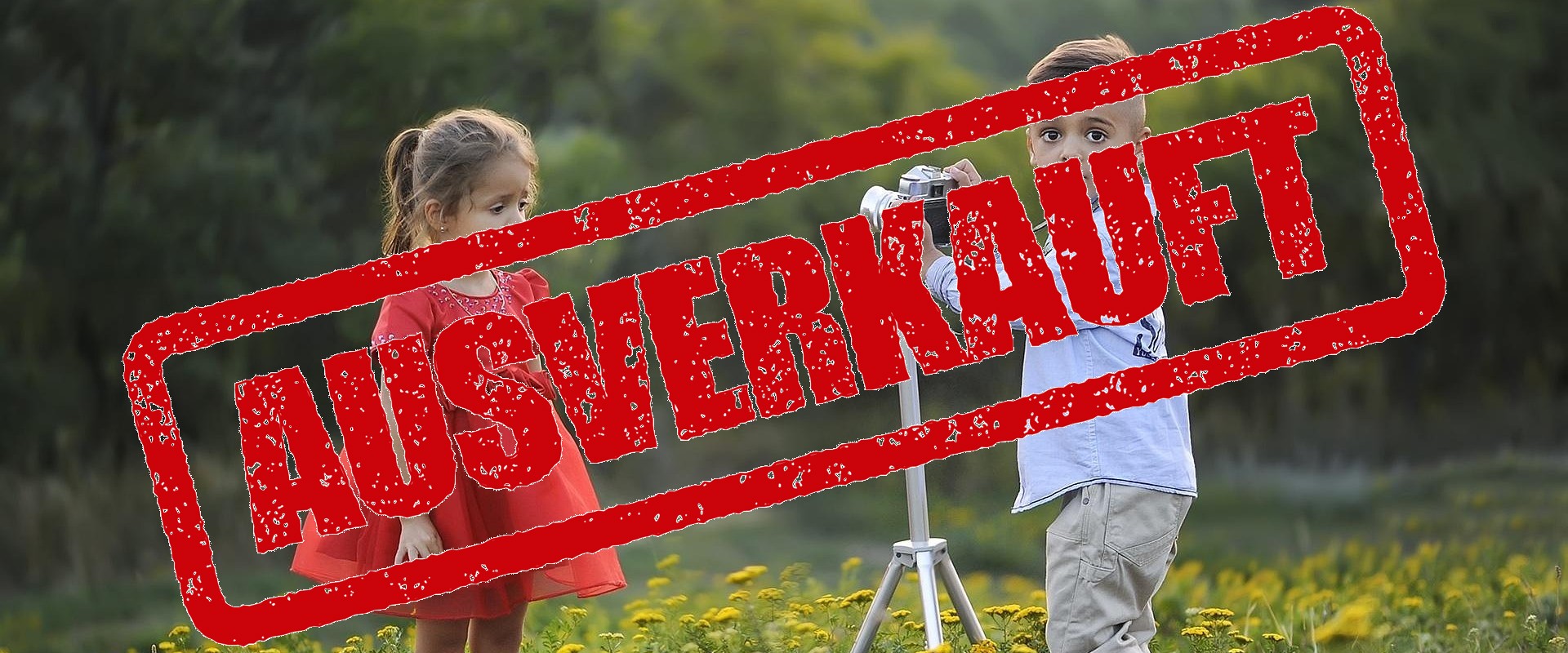 Zwei Kinder in modischen Kleidern stehen auf einer Wiese.