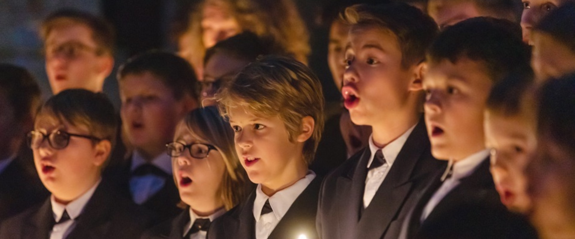 Viele Kinder singen im Kerzenschein.