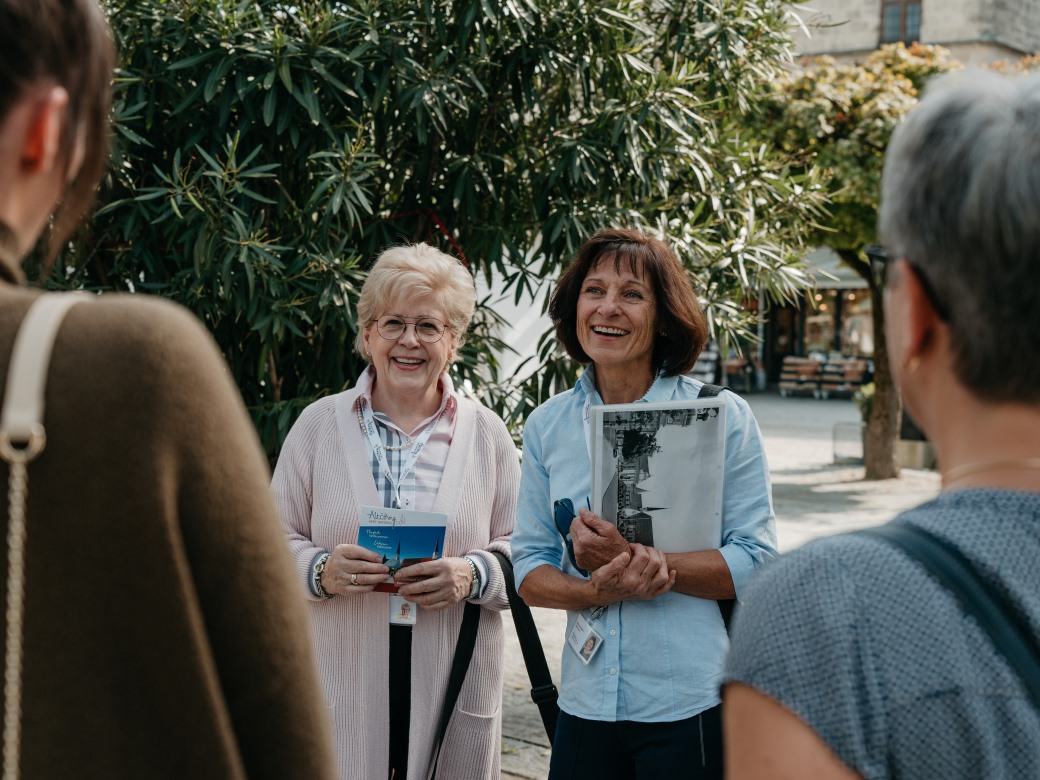 Stadtführung Altötting's starke Frauen, Foto Inn Salzach Tourismus Zwei Stadtführerinnen stehend lachend vor ihrer Frauengruppe.