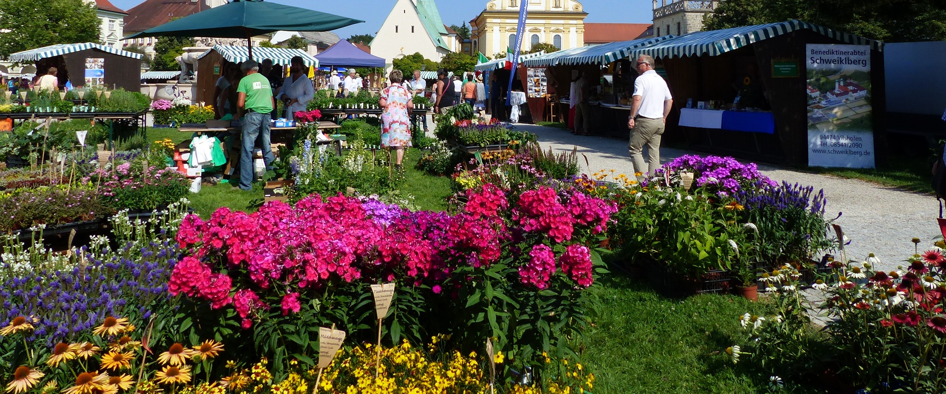 Blumen, Menschen und Gebäude auf dem Altöttinger Kapellplatz.