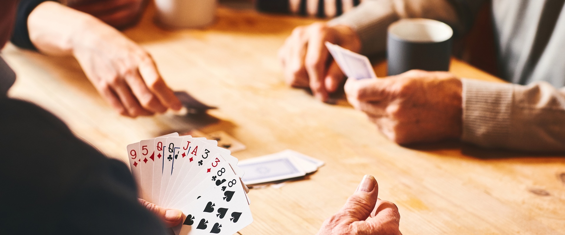 Senioren sitzen an einem Tisch und spielen ein Kartenspiel