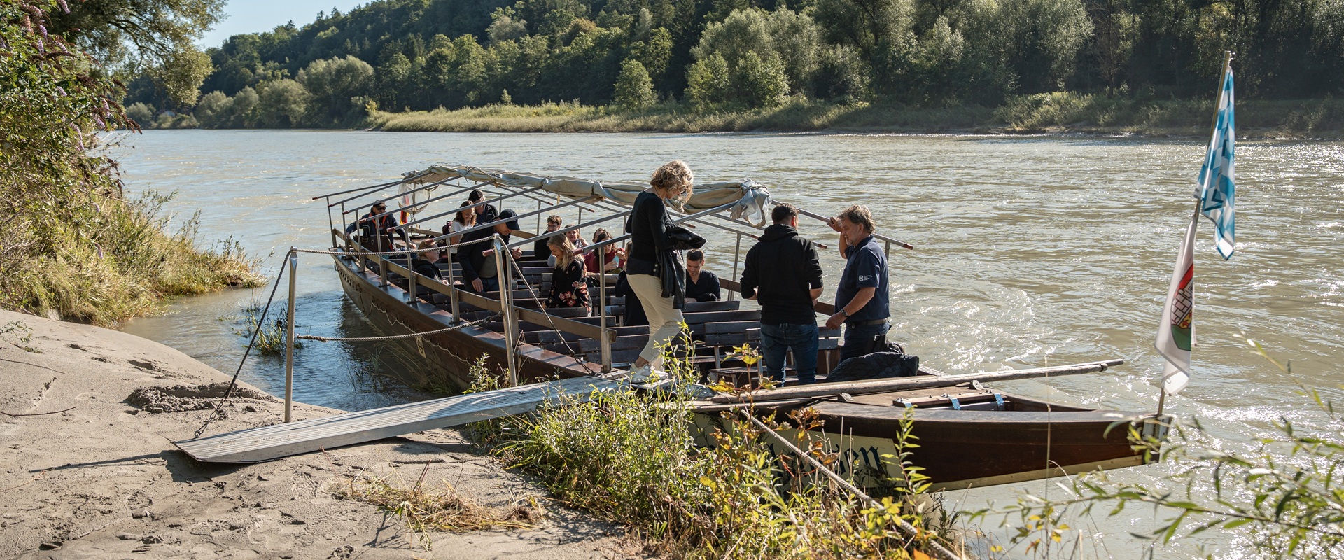 Menschen auf einem Boot am Flussufer.