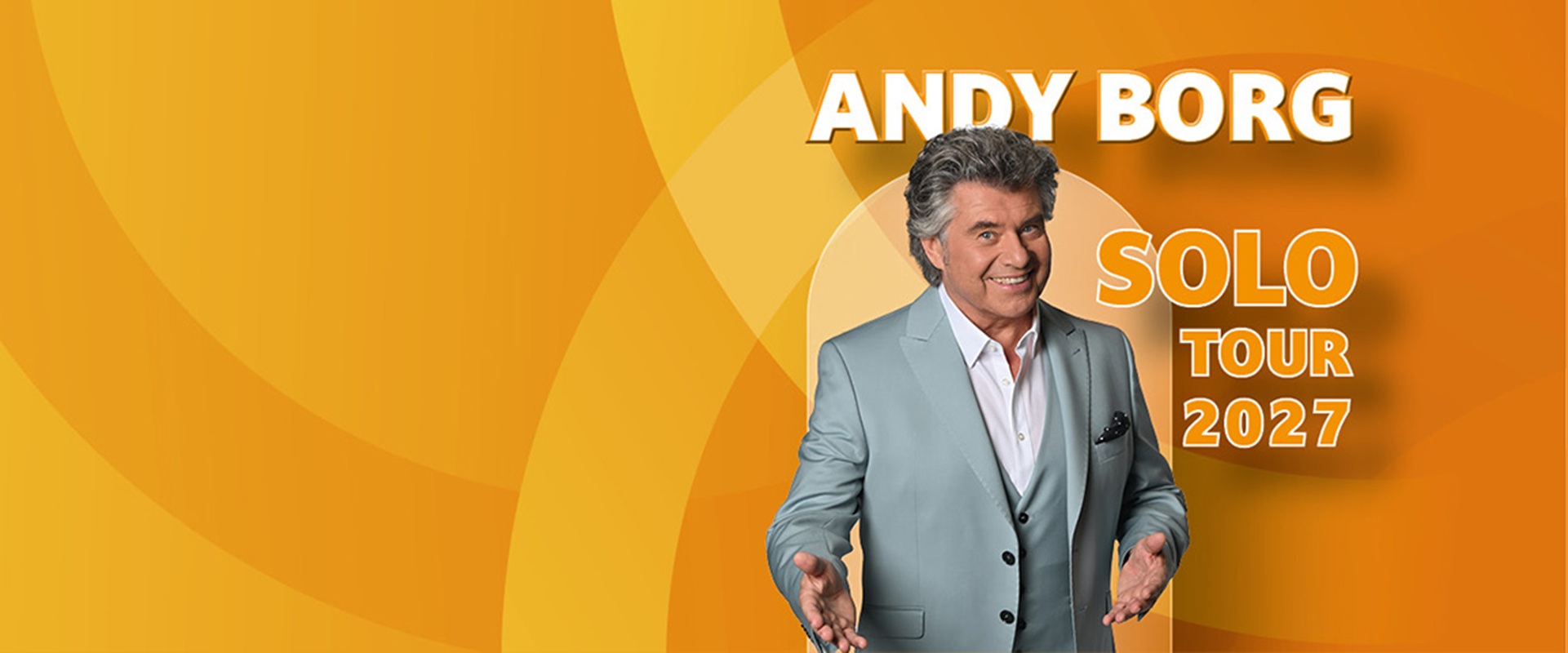 Ein Mann mit grau melierten Haaren und Anzug steht vor einem bunten Hintergrund. 