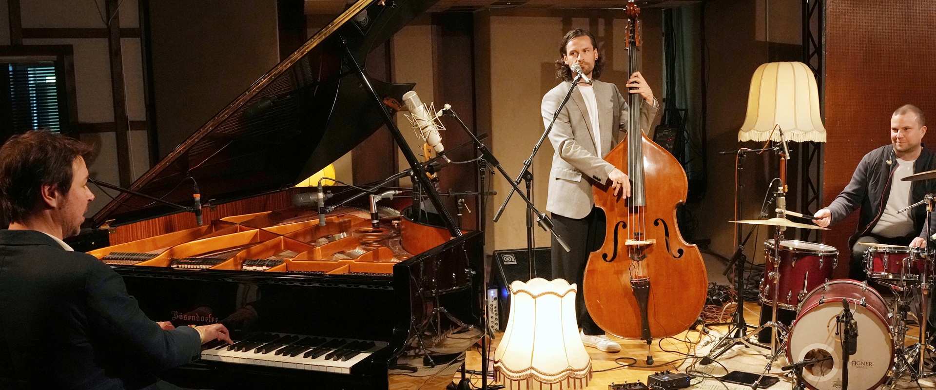 Drei Musiker mit Klavier, Gitarre und am Schlagzeug.