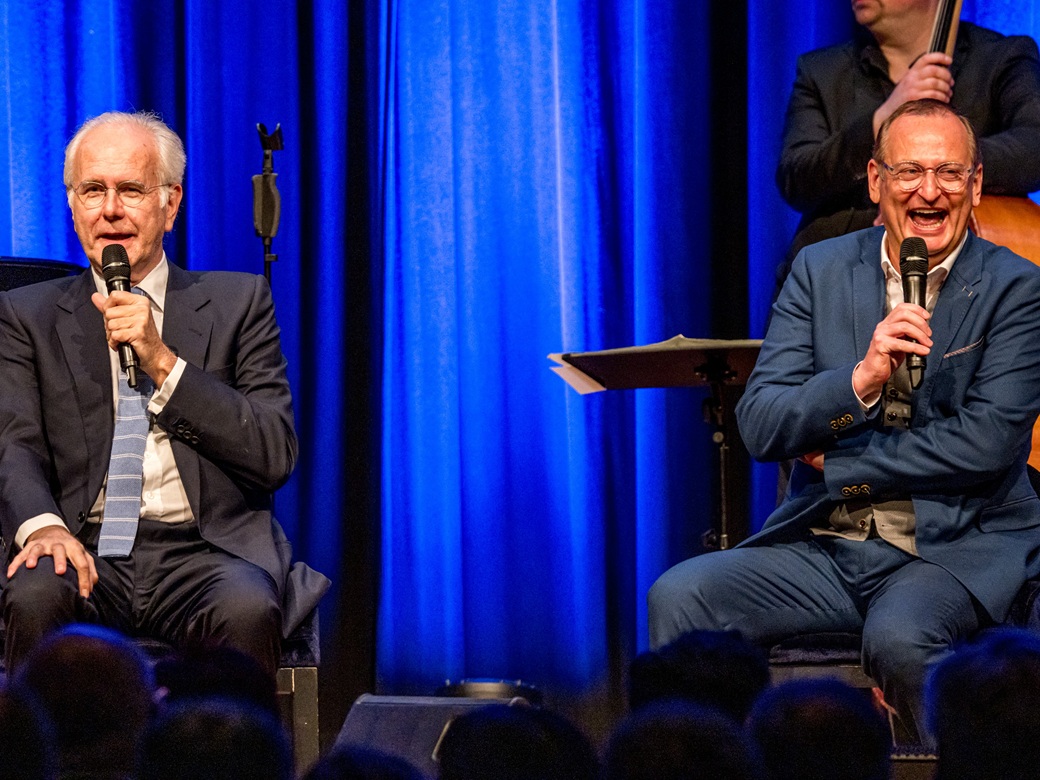 Volker Heißmann, Harald Schmidt, Forum Altoetting, Bild Stephan Weiss Fotodesign Zwei Männer im Anzug sitzen nebeneinander auf der Bühne.