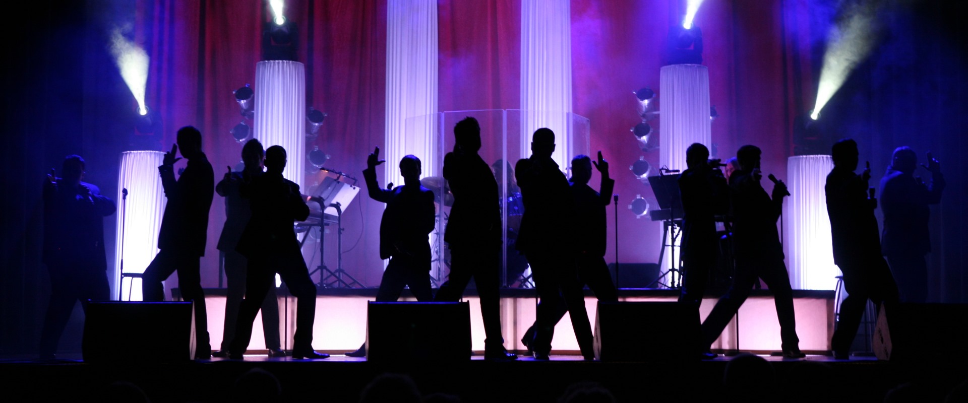 Die 12 Tenors tanzen auf der Bühne in buntem Licht.