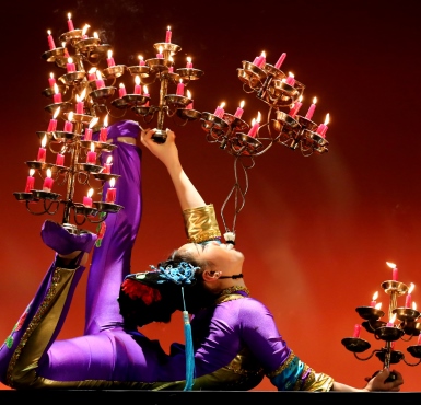Eine Artistin des Chinesischen Nationalcircus trägt Kerzenleuchter mit brennenden Kerzen auf Händen und Füssen gleichzeitig.