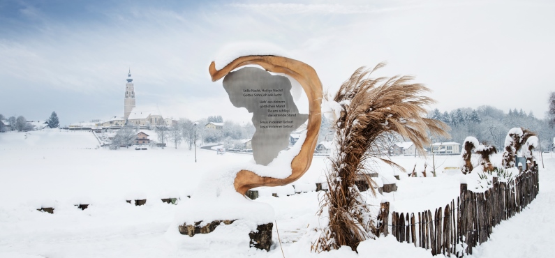 Eine goldene Stele auf dem Friedensweg der Franz Xaver Gruber Gemeinschaft zeigt den Text zum Thema Winter.