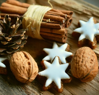 Weihnachtsgebäck, Nüsse und Zimt liegen auf einer Holzplatte.