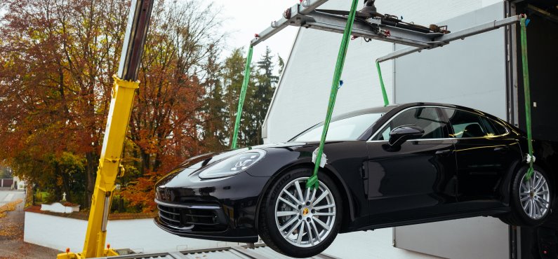 Eine Außenaufnahme, als gerade ein Porsche mit einem Kran ins Altöttinger Forum gehoben wird.