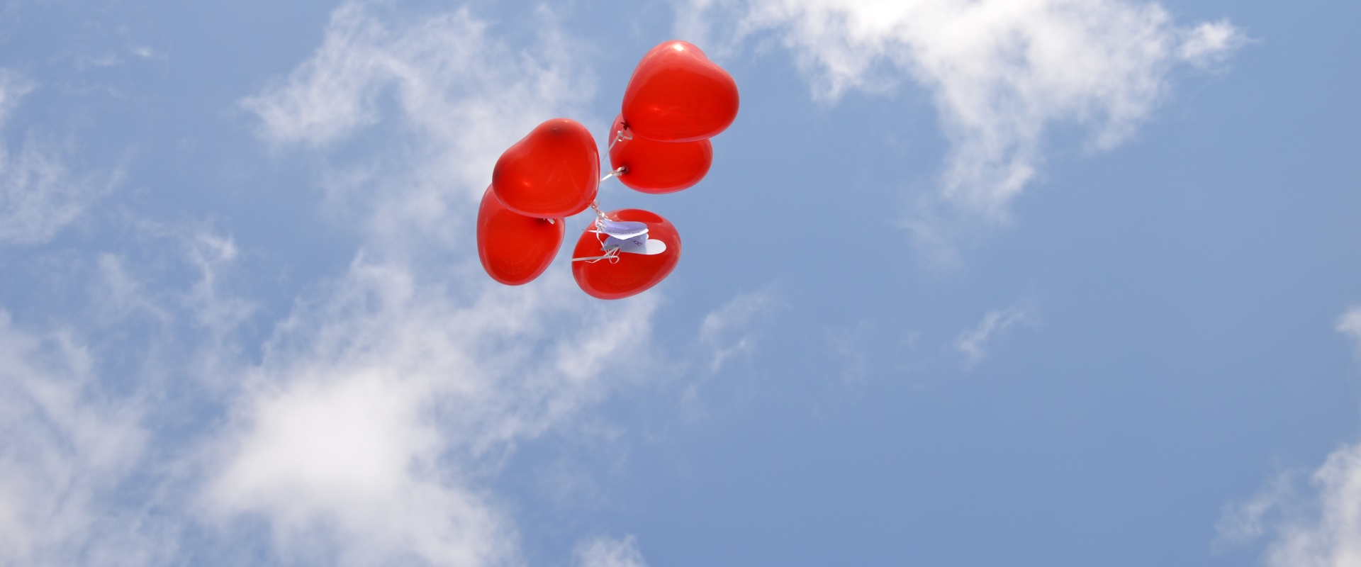 Bei einer Hochzeit im Altöttinger Forum fliegen rote Herzluftballons dem Himmel entgegen.