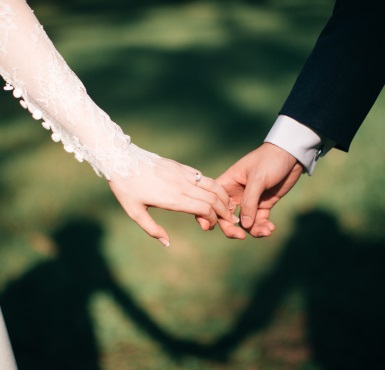 Die Braut und der Bräutigam halten Händchen bei der Hochzeit im Altöttinger Forum.