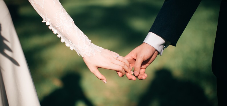 Die Braut und der Bräutigam halten Händchen bei der Hochzeit im Altöttinger Forum.